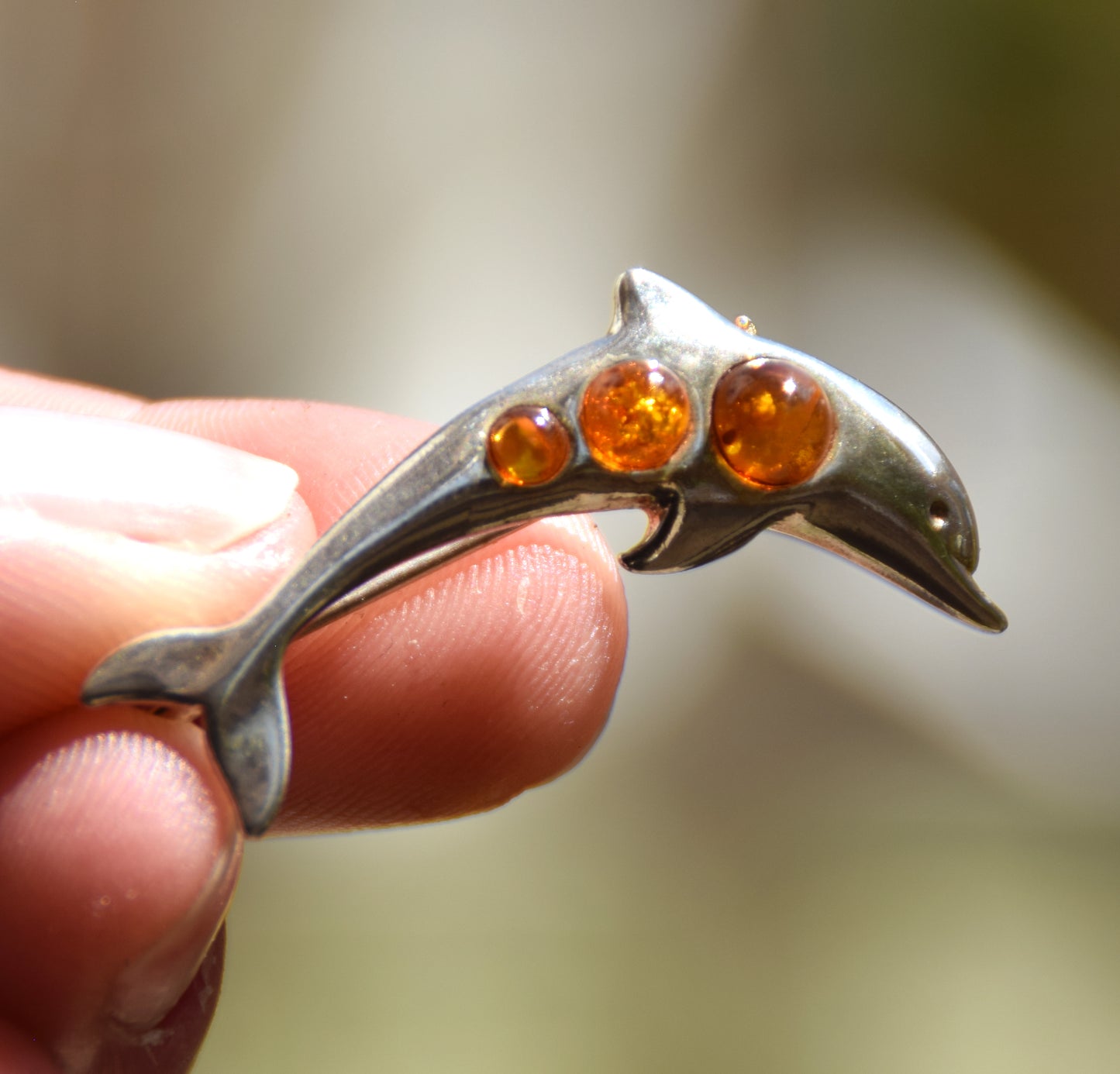 Delicate dolphin-shaped brooch crafted from natural cognac amber and 925 Sterling Silver, MJ Baltica, BBR013